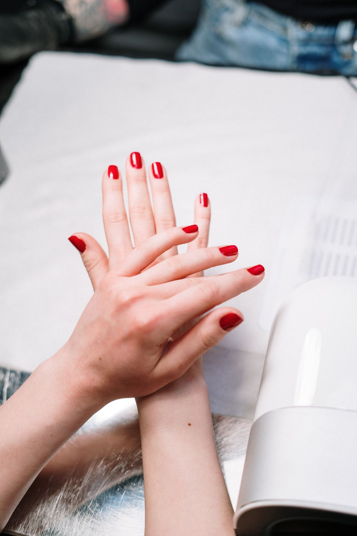 Fresh red manicure near curing lamp